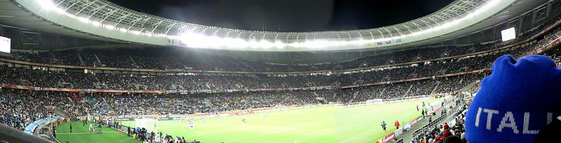 JAR 521.JPG - Stadion v celé své kráse, Kroci si z loajality k novému zaměstnavateli koupil alespoň italskou čepici. A to se mi ještě v Krugerově parku při teplotách 30°C smál, že si do Afriky vezu zimní čepici.